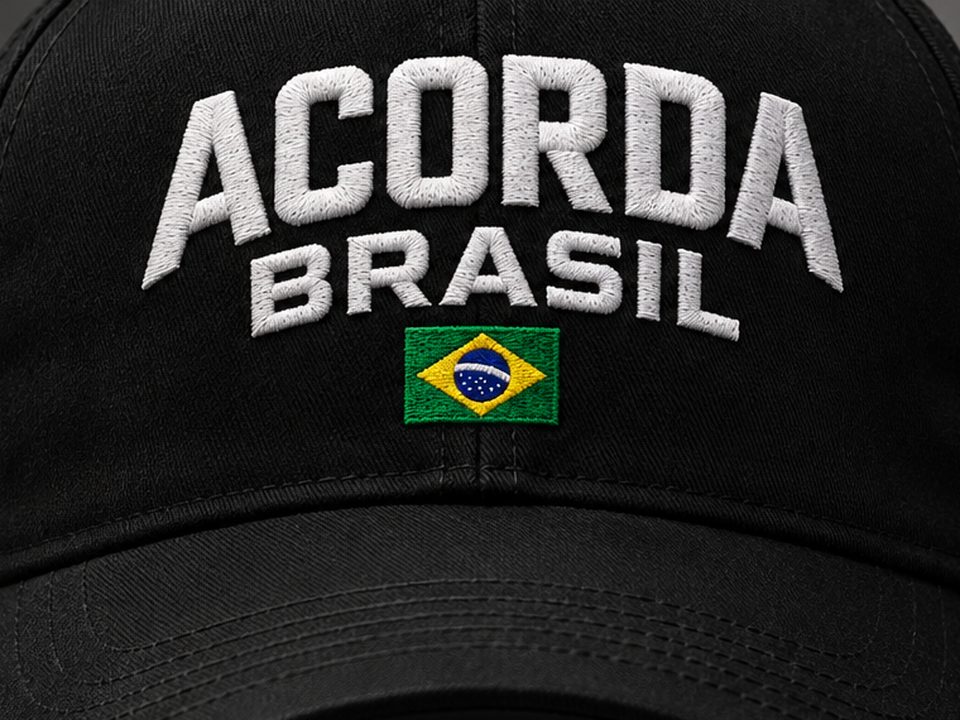 Detalhe do bordado ACORDA BRASIL em branco sobre o boné preto, com a bandeira do Brasil